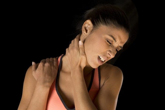 una mujer atlética joven se agarra el cuello y los hombros y hace un gesto de dolor