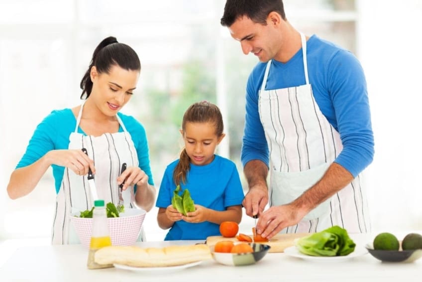 Padres y niños pequeños preparan comida saludable juntos en la cocina