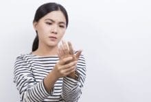 Mujer masajeándose los dedos y la mano para aumentar el flujo sanguíneo