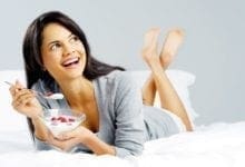Mujer sonriendo y comiendo yogur con bayas