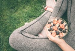 Atleta sentado sosteniendo un plato de avena y bayas en el regazo
