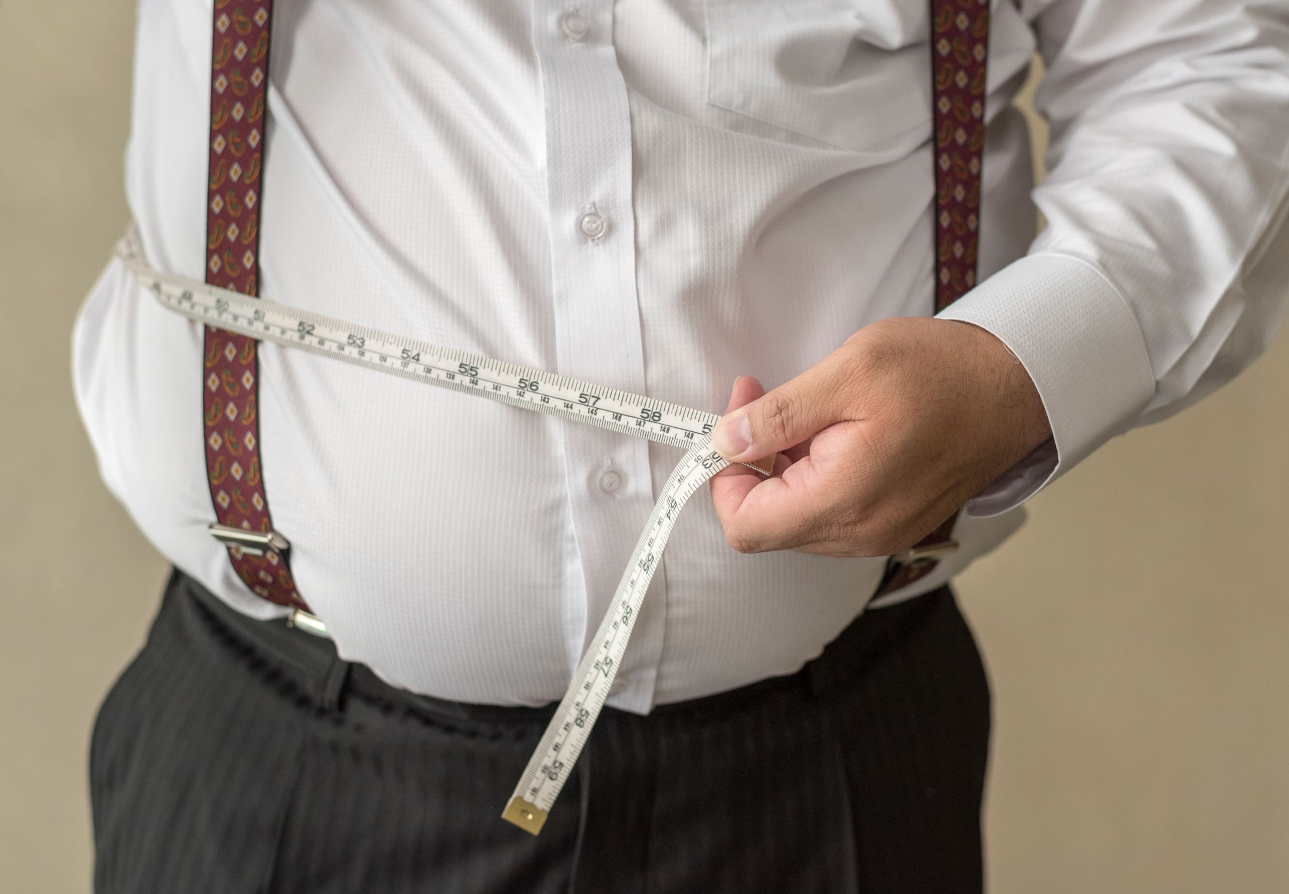 Overweight man holding a measuring tape