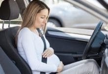 Una mujer embarazada toma su vientre durante una contracción mientras se encuentra sentada en un automóvil