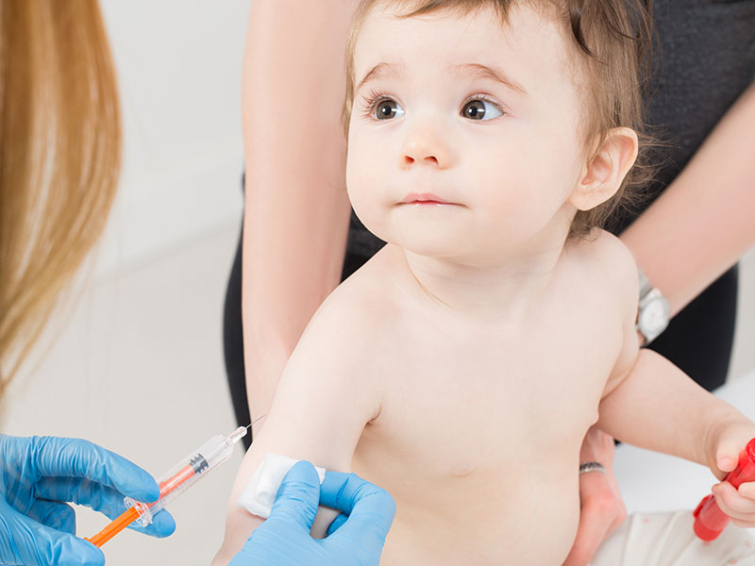 Un médico con guantes está listo para darle una inyección en el brazo a un niño pequeño.