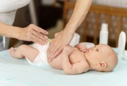 Una madre p cambia el pañal de sus recién nacidos en una manta rosa.